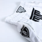 Fighter wearing MTM Essentials Muay Thai Shorts in white, performing a kick